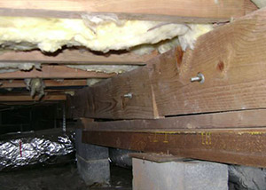 A sagging crawl space with concrete supports and wooden shimming a Woodmere crawl space